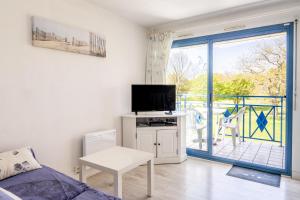 ein Wohnzimmer mit einem TV und einer Glasschiebetür in der Unterkunft 07 - Villa Sainte Marie, Vue golf in Pornic