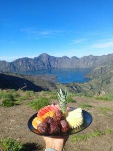 a person holding a plate of fruit on top of a mountain at Oke rinjani in Bayan