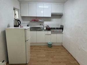 a small kitchen with white cabinets and a refrigerator at Hanok House with a Yard 1 in Seoul