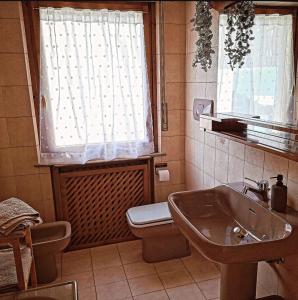 un bagno con lavandino, WC e finestra di Pupili's a Calalzo