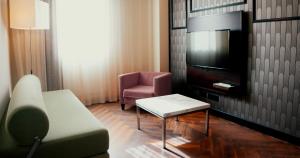 sala de estar con sofá, TV y silla en Vértice Sevilla Aljarafe, en Bormujos