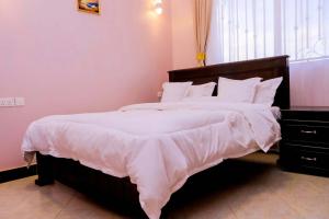 a bedroom with a large bed with white sheets at Kampala Hilltop Haven 2 Bedroom Gem in Kampala