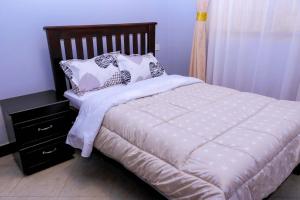a bed with two pillows on top of it at Kampala Hilltop Haven 2 Bedroom Gem in Kampala