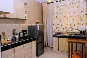 a kitchen with a sink and a refrigerator at Kampala Hilltop Haven 2 Bedroom Gem in Kampala