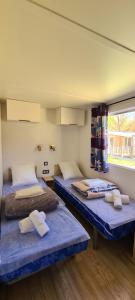 a room with two beds and a window at Camping La Grand'Terre 4 étoiles - Linge de maison inclus - Clim - TV - Plancha - Lave-vaisselle - 4 personnes 2 chambres in Ruoms +55 photos