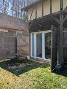 a house with a door and a table and a bench at La sellerie - small barn in Saint-Aubin-Epinay