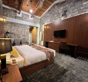 KhapaluDestination Hotel Khaplu的一间带床、书桌和电视的卧室