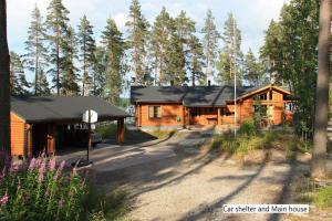 a couple of log cabins in a forest at Spacious villa with great scenery and nature in Pertunmaa