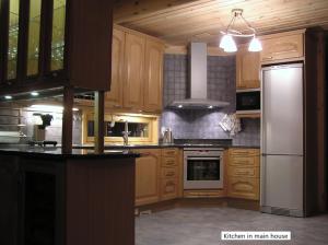 a kitchen with wooden cabinets and a white refrigerator at Spacious villa with great scenery and nature in Pertunmaa