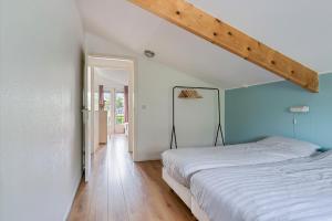 a bedroom with a white bed and a wooden floor at Huis Specht is perfect voor vakantie nabij meer en tuin op zuiden in Grou