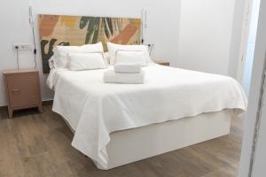 a white bed with white sheets and pillows on it at Torre Solana 41 in Cádiz