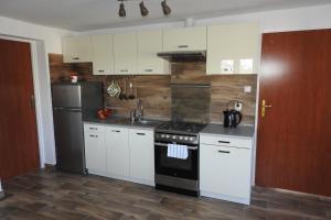 a kitchen with white cabinets and a black stove top oven at Pokoje Gościnne Pod Brzózką in Poledno
