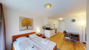 a bedroom with a bed and a table and a kitchen at Cute and central studio - Sun 11 in Zurich