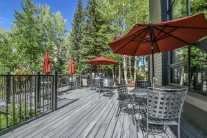 a deck with tables and chairs and umbrellas at Pines 2161 by SummitCove Lodging in Keystone