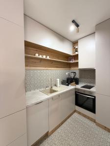 セゲドにあるPosh Cat City Apartmentの白いキャビネットとシンクのあるキッチン