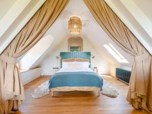 a bedroom with a blue bed in a attic at Vineyard View - Otium Wine Estate in West Worldham