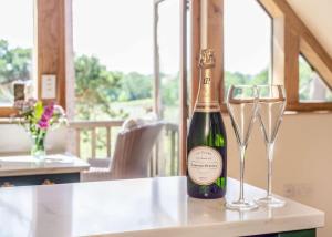 a bottle of champagne and two glasses on a counter at Vineyard View - Otium Wine Estate in West Worldham