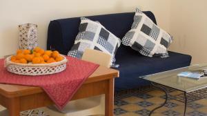 パレルモにあるMassimissimoの青いソファ(枕付)、オレンジのボウル1杯(テーブル上)
