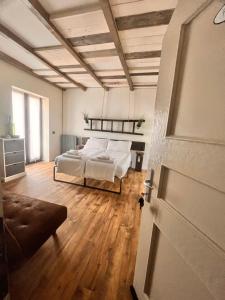a bedroom with a bed with white sheets and wooden floors at Stanza in sondrio Coel in Sondrio