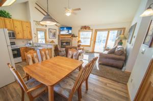 a kitchen and living room with a wooden table and chairs at Snake River 44 by SummitCove Lodging in Keystone