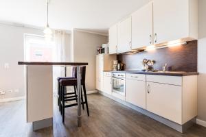 a kitchen with white cabinets and a bar with a stool at Fehmarnstrand 78 App 9 in Staberdorf