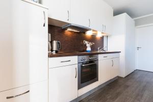 a kitchen with white cabinets and a stove at Fehmarnstrand 78 App 9 in Staberdorf