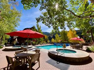 une piscine avec une table, des chaises et un parasol dans l'établissement Arapahoe Lodge 8105 by SummitCove Lodging, à Keystone