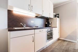 a kitchen with white cabinets and a sink at Fehmarnstrand 78 App 12 in Staberdorf