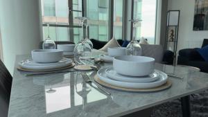 a table with plates and bowls and glasses on it at Central M K 2-Bedroom Apartment Sleeps 4 Parking in Milton Keynes
