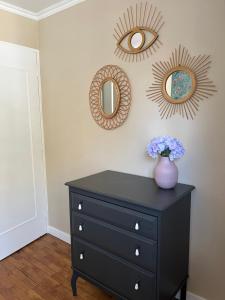 a black dresser with two mirrors and a vase with flowers at New & Cozy in Lyon
