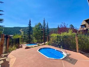 Dos piscinas en un patio trasero con valla. en Tenderfoot Lodge 2620 by SummitCove Lodging, en Keystone
