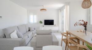 トロクスにあるGran Apartamento Laguna Beachのソファとテーブルのある白いリビングルーム