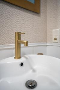 トロクスにあるGran Apartamento Laguna Beachの白いバスルームの洗面台(金の蛇口付)