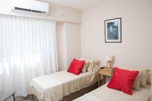 a bedroom with two beds with red pillows at Amplio dpto-Hipódromo San Isidro in Acassuso