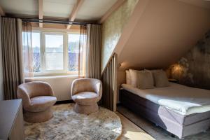 a bedroom with a bed and two chairs and a window at Boutique Hotel, Restaurant & Wellness Westerburcht in Westerbork