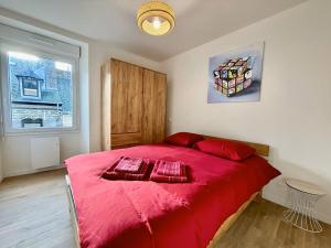 a bedroom with a large red bed with red pillows at Coeur de ville in Saint-Brieuc