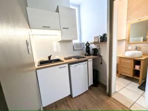 a small kitchen with white cabinets and a sink at Le Nid - studio cosy fraîchement rénové in Saint-Brieuc