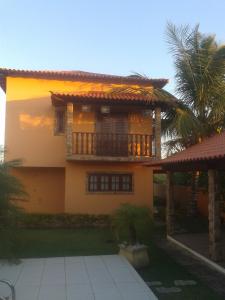 ein Haus mit einem Balkon und einer Palme in der Unterkunft Casa Alto Padrão Casa Laranja in Praia Sêca