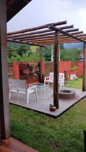 eine Terrasse mit zwei weißen Bänken und einer Feuerstelle in der Unterkunft Casa Quinta do Paiol in São Bento do Sapucaí