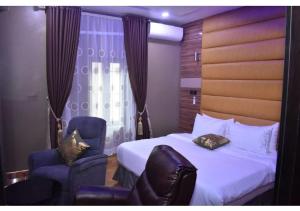 a hotel room with a bed and two chairs at Grand Diamond Hotels & Suites LTD in Owerri