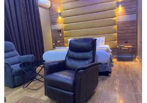 a hotel room with a bed and a chair at Grand Diamond Hotels & Suites LTD in Owerri