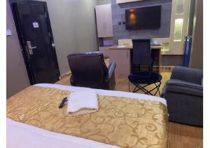 a room with a bed and two chairs and a table at Grand Diamond Hotels & Suites LTD in Owerri