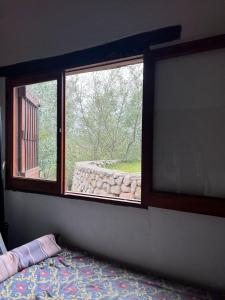 a bedroom with a window with a view of a stone wall at La Ramada in Tafí del Valle