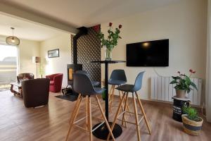un soggiorno con sedie e TV a parete di Maison spacieuse avec spa , sauna au pays des Abers ,10 min des plages Bretagne a Lannilis