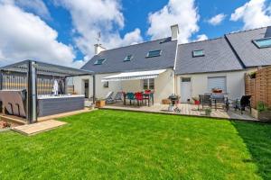 un ampio cortile con terrazza e prato di Maison spacieuse avec spa , sauna au pays des Abers ,10 min des plages Bretagne a Lannilis