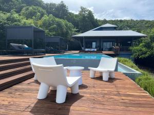 a patio with white chairs and a swimming pool at La Belle Dame in Deshaies