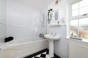 a white bathroom with a sink and a bath tub and a sink at JOIVY Greenknowes Lodge with Hot Tub and Wood Burning Stove in Kelty