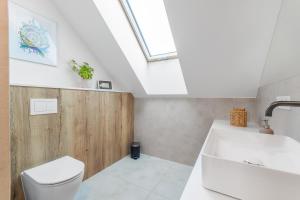 a bathroom with a toilet and a sink and a skylight at Apartamenty Dwie Sosny in Junoszyno +56 photos