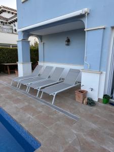a group of chairs sitting under a blue wall next to a pool at Mar Menor Golf Resort , La maison bleue, villa piscine privée in Los Martínez