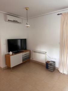a living room with a flat screen tv on a white wall at Mar Menor Golf Resort , La maison bleue, villa piscine privée in Los Martínez